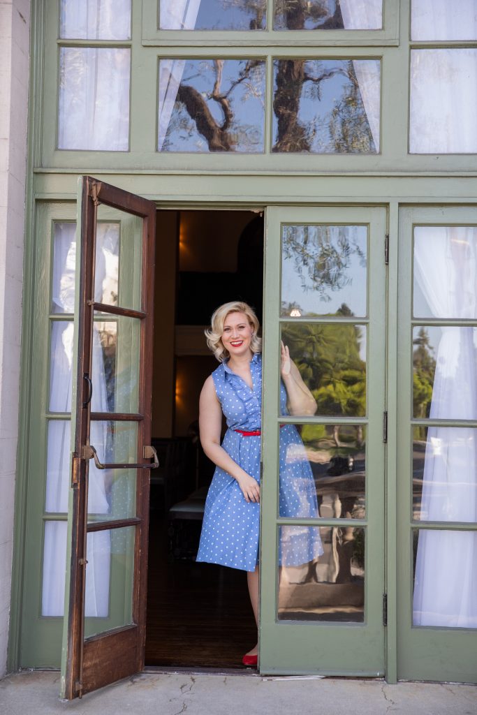women in blue dress standing in glass doorway