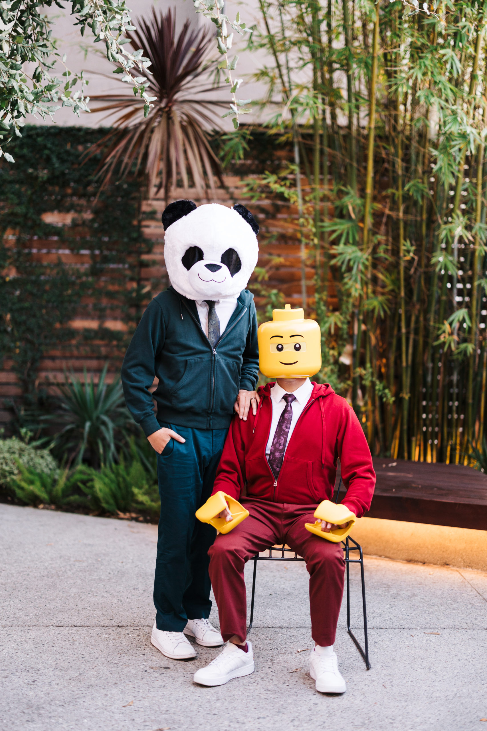 two men standing and sitting dresses as a panda and a lego character